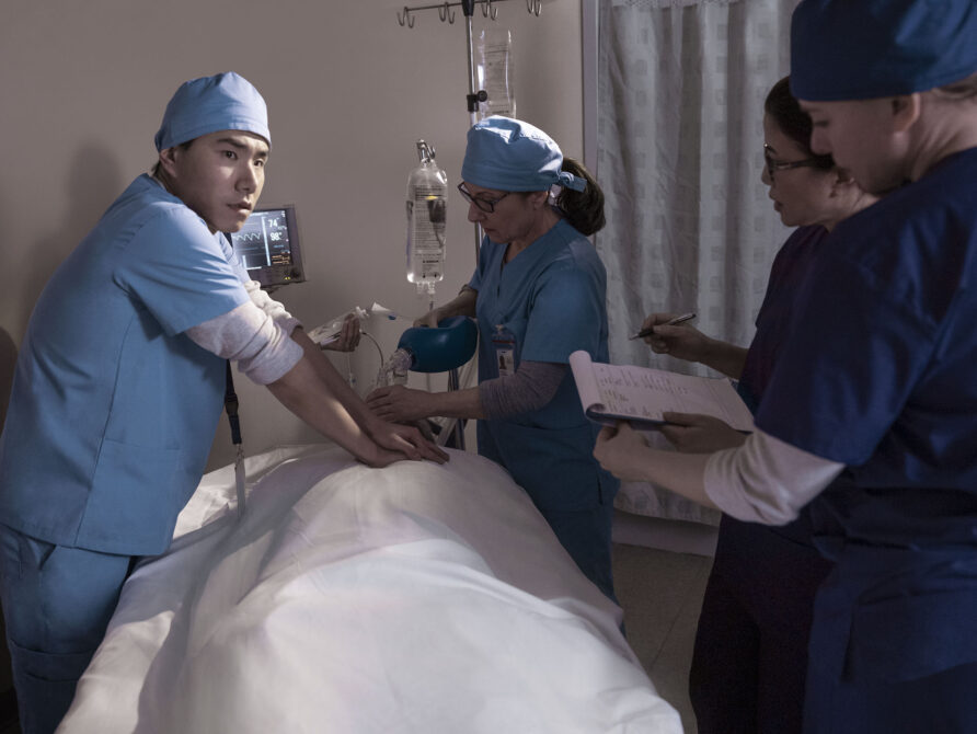 Doctors and clinicians working with patient in operating room.
