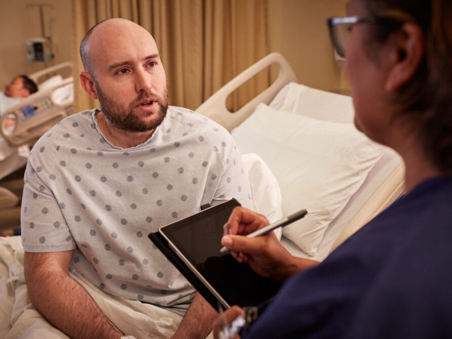 Image of nurse and patient. Nurse is using EHR tool on tablet