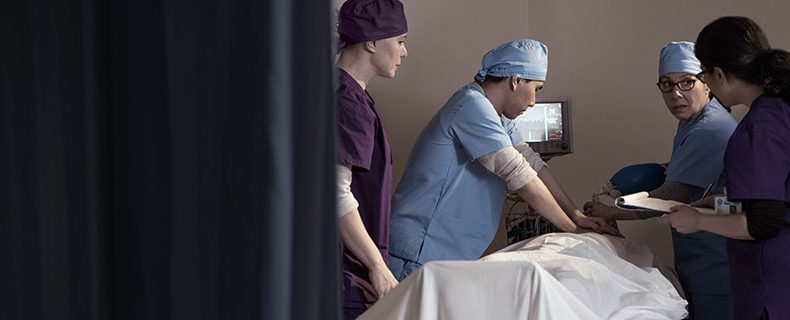 Doctors and nurses treating patient in hospital room