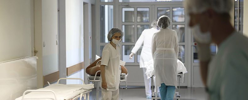 Doctors in white coats carry the patient on a stretcher.