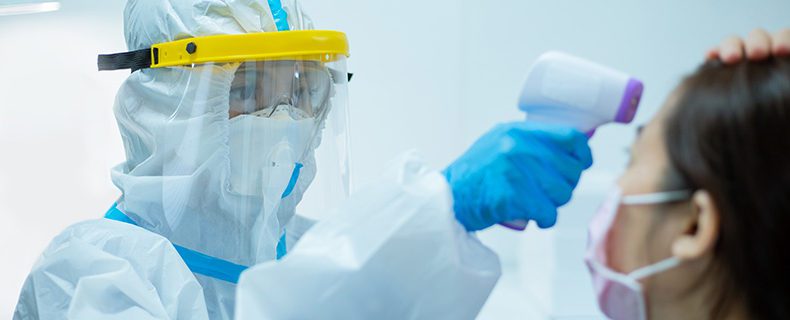 Doctor using thermometer gun on patient's forehead