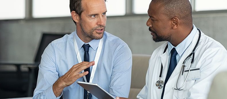 Doctor talking with individual about patient care.