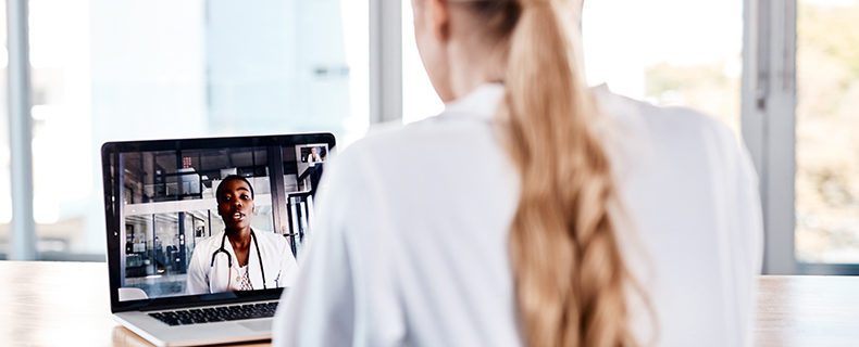 Doctor talking to another doctor via telehealth app on laptop.