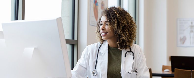 Doctor using EHR tool to view patient records on computer.